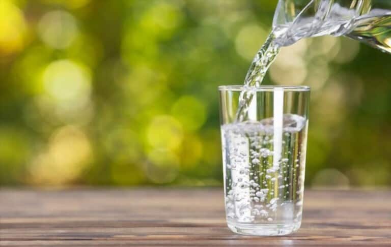 water jug pouring into glass on table water jug pouring into glass on table
