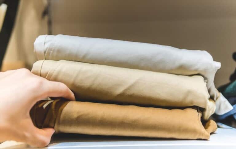 hand grabbing one of the stacked casual pants hand grabbing one of the stacked casual pants