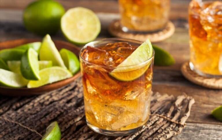 Glass of rum garnished with lemon on a wooden table Glass of rum garnished with lemon on a wooden table