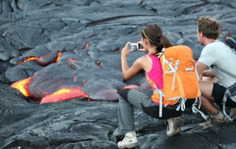 Hawaii lava tourism. Tourists take pictures of lava flowing from Kilauea volcano around Hawaii Volcanoes National Park, USA.