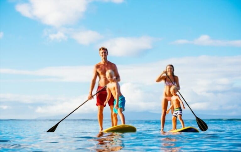 Happy family standing up and rowing together on the ocean on a sunny morning Happy family standing up and rowing together on the ocean on a sunny morning
