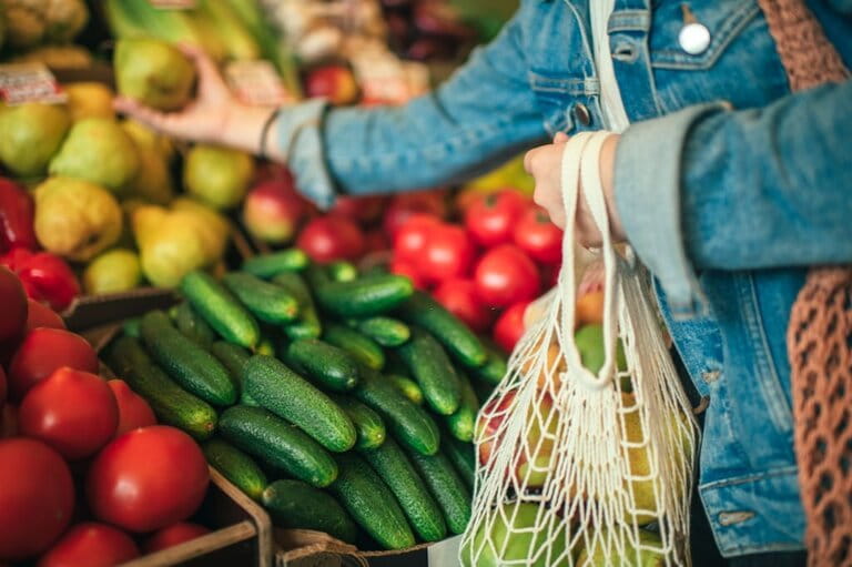 image of a woman with an eco-friendly bag picking fruit at a farmers market at Windward Mall image of a woman with an eco-friendly bag picking fruit at a farmers market at Windward Mall