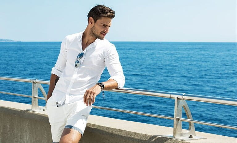 Handsome man in white clothes posing in sea landscape