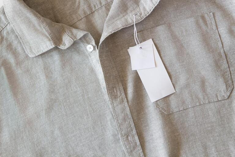 Blank price label tag paper card on natural linen shirt. Clothes label tag mockup template with copy space for brand, text, price. Blank price label tag paper card on natural linen shirt. Clothes label tag mockup template with copy space for brand, text, price.