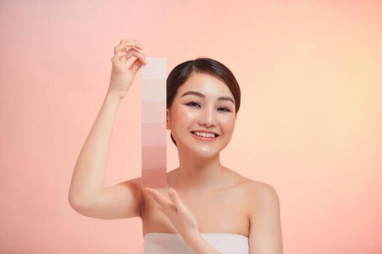 Portrait of beautiful young woman hold different tones of skin color scale on paper Portrait of beautiful young woman hold different tones of skin color scale on paper