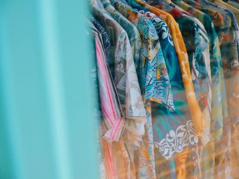 Vintage Hawaiian style colourful summer surf shirts on a rack in a summertime vintage retro clothes shop - summer shirt wardrobe