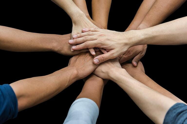 Image of group of overlapping hands against black background Image of group of overlapping hands against black background