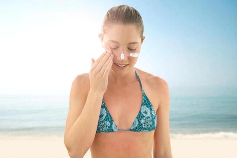Woman applying sunscreen to her face. Woman applying sunscreen to her face.