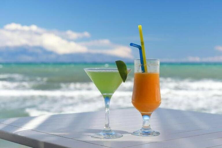 Lime cocktail and orange juice against the sea