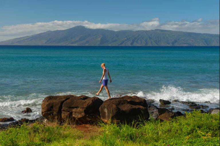 USA, Hawaii, Maui, Kaanapali, girl walking on cliffs with island of lanai in the background