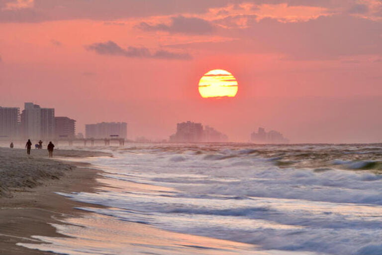 Bright sunrise, with clouds, along beach over Atlantic Ocean with waves breaking along shoreline, in Gulf Shores, Orange Beach, Alabama, USA Bright sunrise, with clouds, along beach over Atlantic Ocean with waves breaking along shoreline, in Gulf Shores, Orange Beach, Alabama, USA
