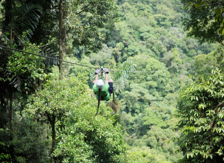 Girl riding a zipline above the rainforest canopy, La Fortuna, Costa Rica