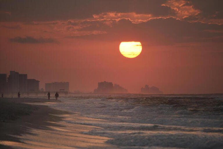 Bright sunrise, with clouds, along beach over Atlantic Ocean with waves breaking along shoreline, in Gulf Shores, Orange Beach, Alabama, USA Bright sunrise, with clouds, along beach over Atlantic Ocean with waves breaking along shoreline, in Gulf Shores, Orange Beach, Alabama, USA