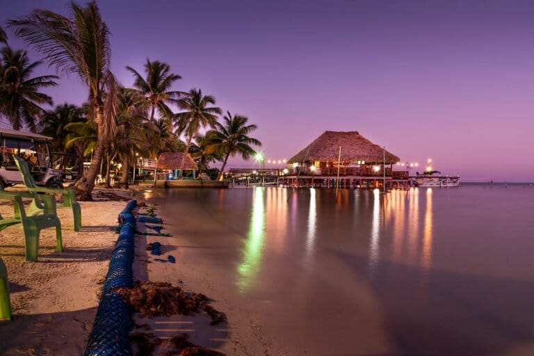 View of beautifully lit overwater bungalow at sunset in Belize