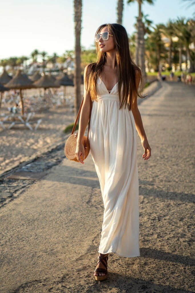 Beautiful brunette woman walking on sunset beach in fashionable maxi dress, relaxing on luxurious tropical summer vacation. Beautiful brunette woman walking on sunset beach in fashionable maxi dress, relaxing on luxurious tropical summer vacation.
