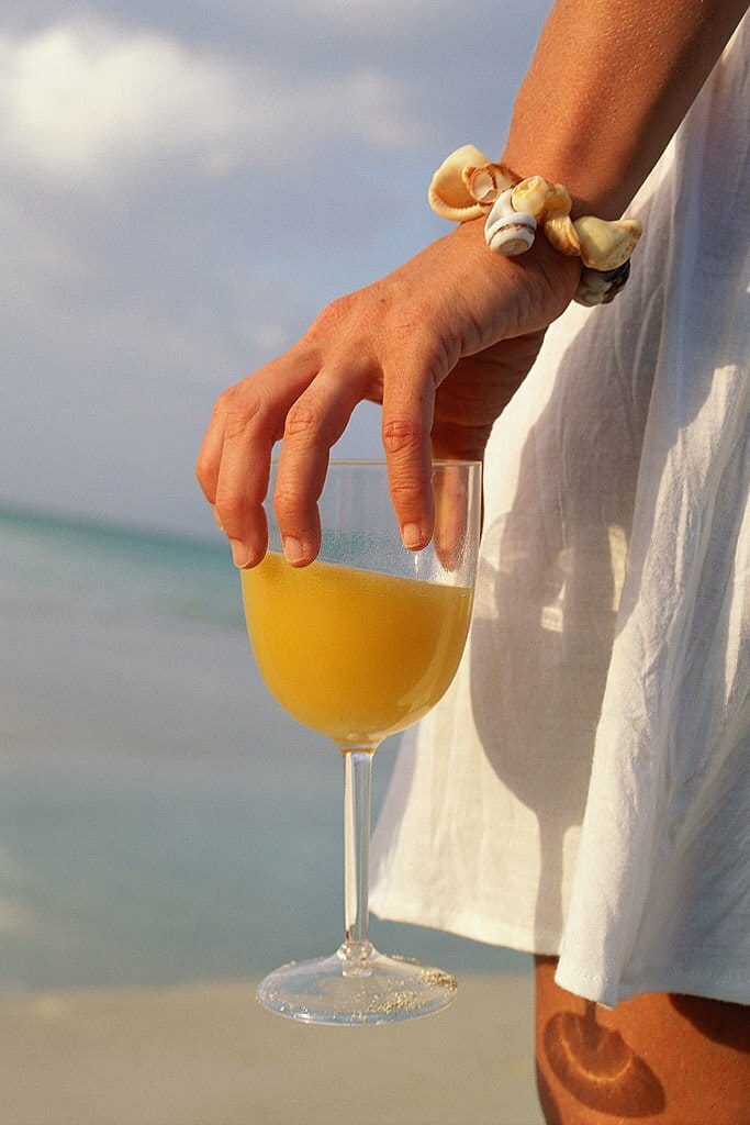 Hand of woman on beach carrying glass with drink Hand of woman on beach carrying glass with drink