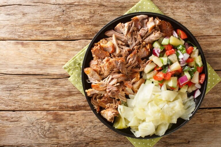 Hawaiian dish Kalua pork slowly cooked and served with stewed cabbage and fresh salad close up on a plate.