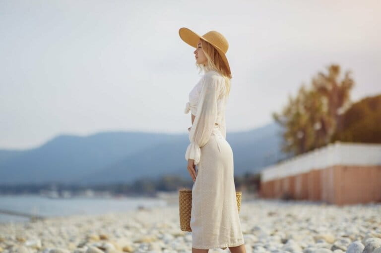 Woman in elegant beach outfit outdoors against palm tree on background during summer vacation Woman in elegant beach outfit outdoors against palm tree on background during summer vacation