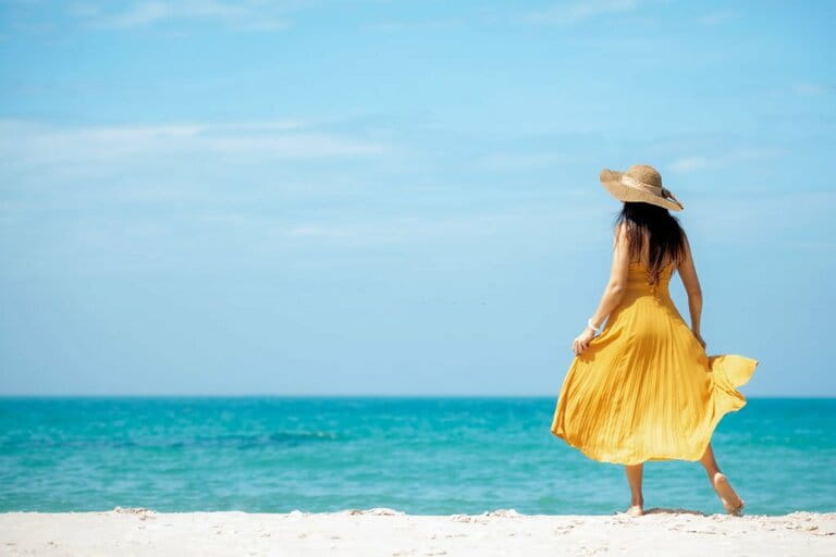 Summer holiday. Lifestyle woman relaxing and relaxing on beach background. Asian happy young people wearing fashionable yellow dresses summer trip walking enjoying tropical beach. Summer holiday. Lifestyle woman relaxing and relaxing on beach background. Asian happy young people wearing fashionable yellow dresses summer trip walking enjoying tropical beach.