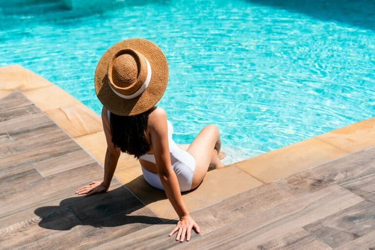Beautiful girl in swimsuit relaxing by the pool during summer vacation. Copy space. Summer and vacation, sunbathing health care Lifestyle concept Beautiful girl in swimsuit relaxing by the pool during summer vacation. Copy space. Summer and vacation, sunbathing health care Lifestyle concept